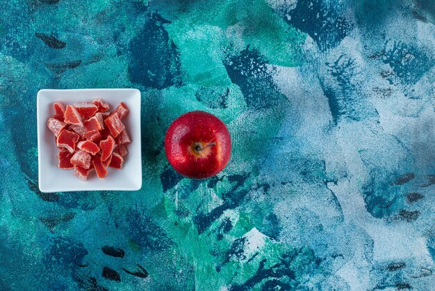 青いテーブルの上に、ボウルにリンゴと赤いマーマレード。
