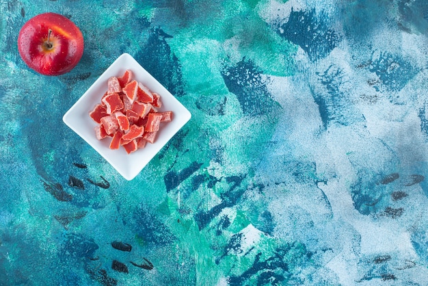 파란 테이블에 있는 그릇에 사과와 빨간 마멀레이드.