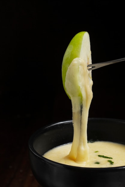 Apple slice dipped in melted cheese