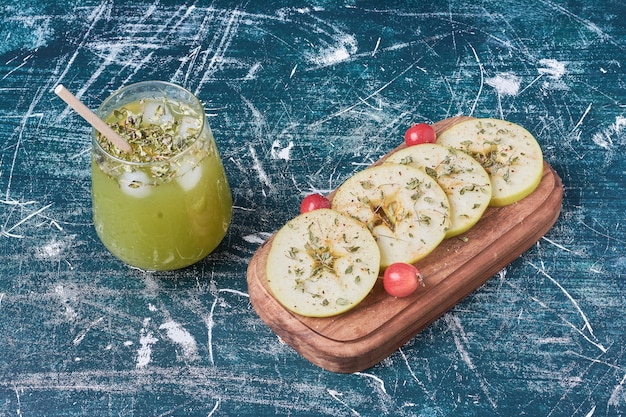 Apple slices with a cup of drink on blue.