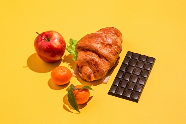 Apple, tangerines, chocolate and croissant