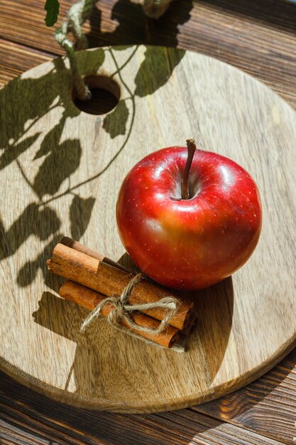 Apple with leaves, cinnamon sticks on wooden cutting board