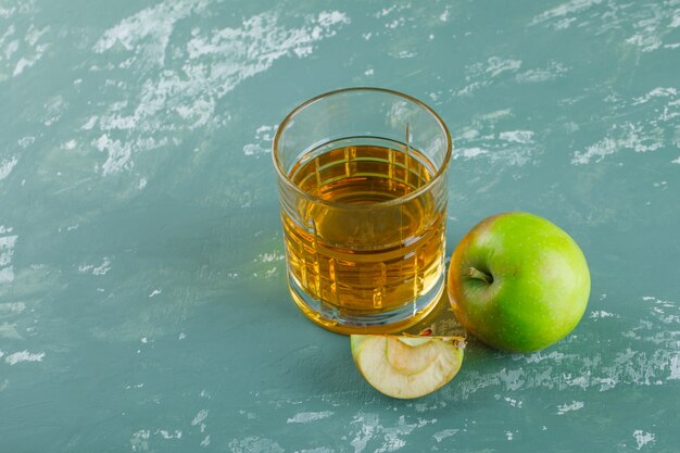 Яблоко с ломтиком, напиток под высоким углом зрения на фоне гипса