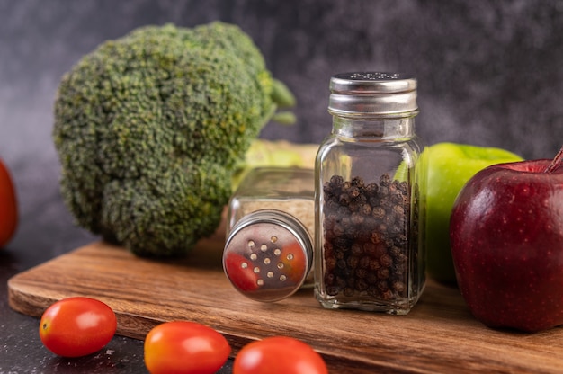 Free photo apple on a wooden board with a jar of pepper seeds