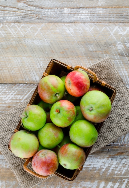 Apples in a basket on wooden and placemat, top view.