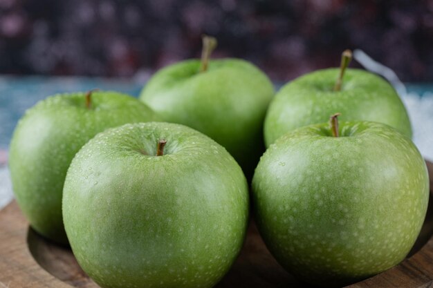 Apples beong served on round wooden plate.