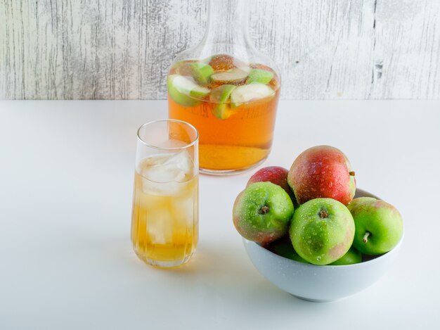 Apples in a bowl with drinks high angle view on white and grungy