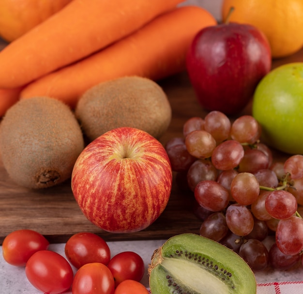 Apples, grapes, carrots and oranges placed together on the ground.