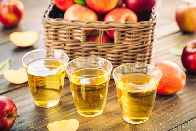 Free photo apples juice in glass with apple in the basket