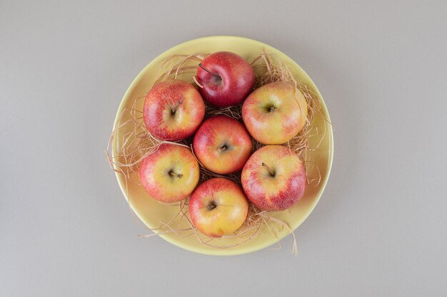 Apples and straw in a bowl on marble 