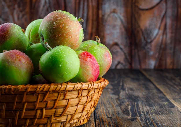 Apples in a wicker basket side view on  old wooden background