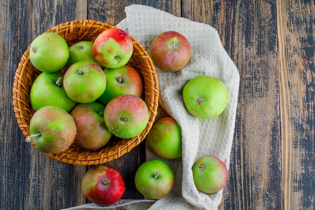 Apples in a wicker basket on wooden and kitchen towel background. flat lay.