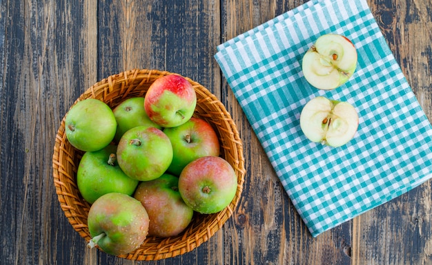 Яблоки в плетеной корзине на деревянном фоне ткани и пикника. вид сверху.