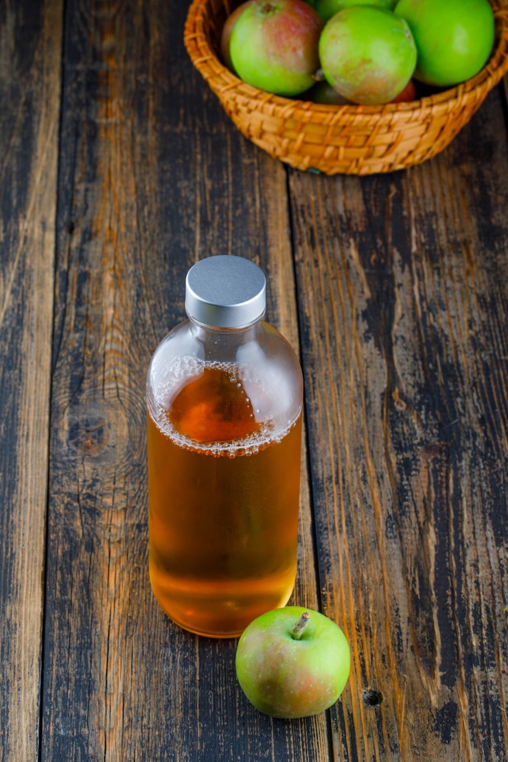 मुफ़्त फोटो apples with bottle of drink in a basket on wooden background, high angle view.