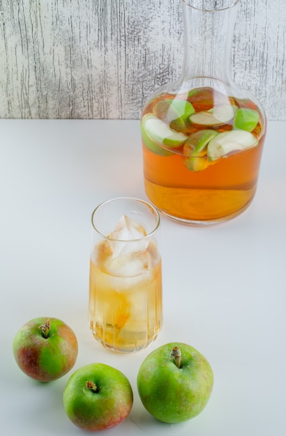 Apples with drinks on white and grungy, high angle view.