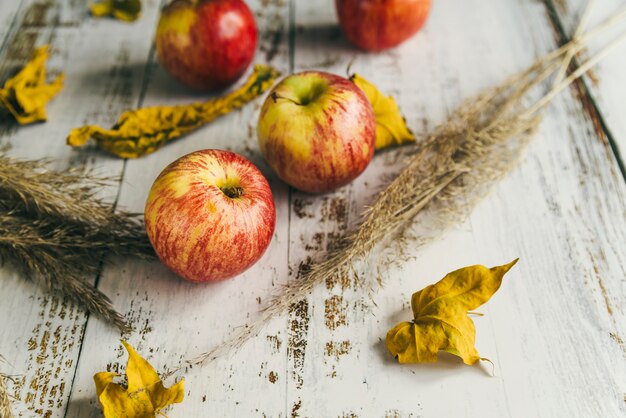 ぼろぼろのテーブルの上の乾燥葉とりんご