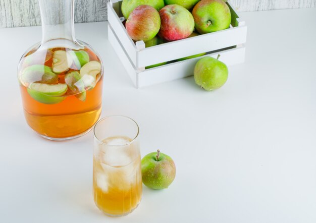 Apples in a wooden box with drink high angle view on white and grungy