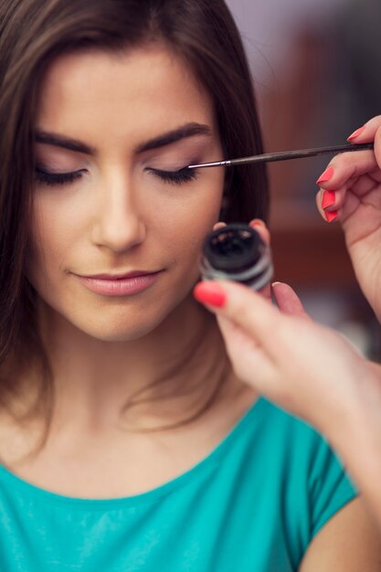 Applying eyeliner from inkwell by makeup brush
