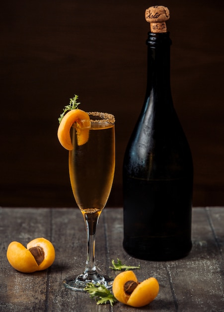 Apricot champagne in champagne glass garnished with apricots on wood counter