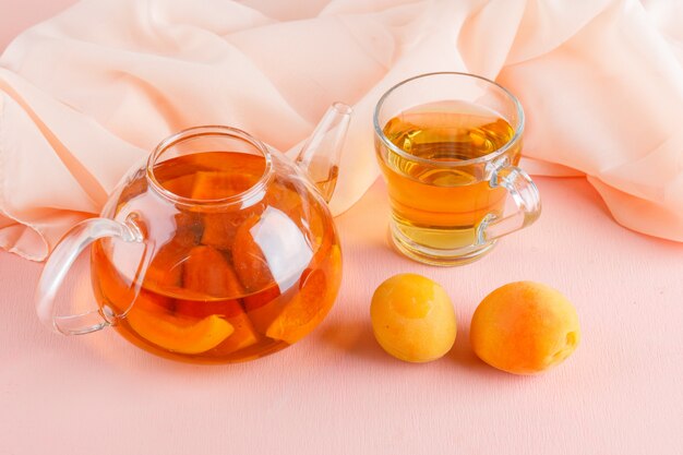 Apricot tea with apricots in teapot and mug, top view.