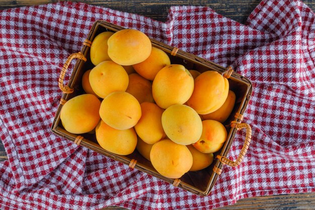 Apricots in a basket on picnic cloth and wooden table. flat lay.