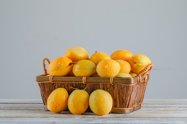 Apricots in a basket on wooden table. side view.