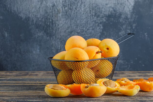 Apricots in a colander on wooden and plaster wall. side view.