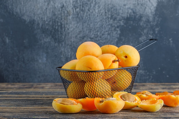 Apricots in a colander on wooden and plaster wall. side view.