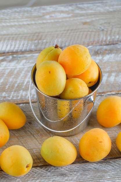 Apricots in a mini bucket on a wooden table. top view.