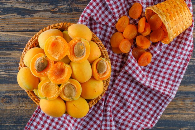 Apricots in a wicker basket with dried apricots flat lay on wooden and picnic cloth