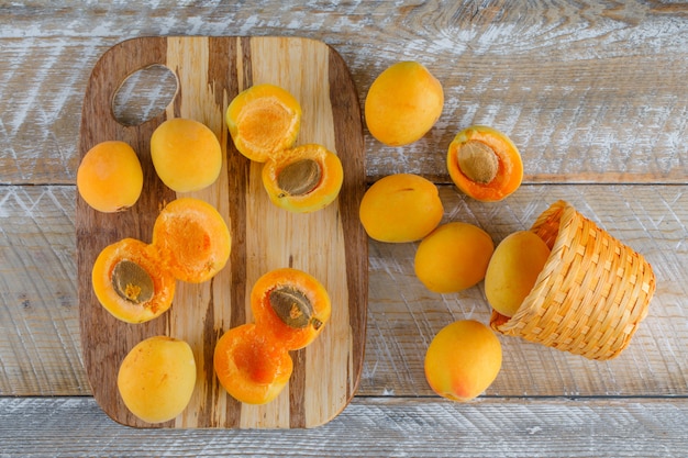 Apricots in a wicker basket on wooden and cutting board. flat lay.