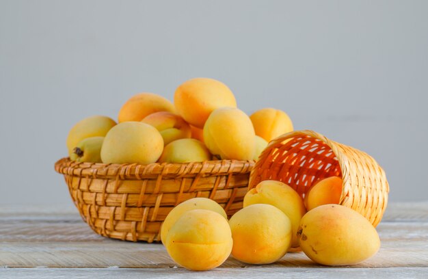 Apricots in wicker baskets on wooden table. side view.