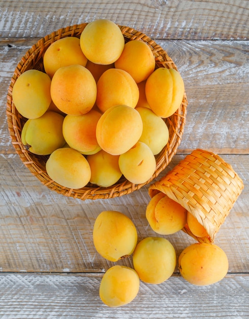 Apricots in wicker baskets on a wooden table. top view.