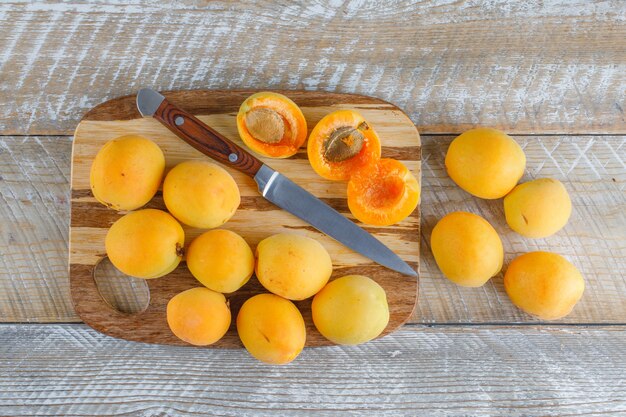 Apricots with knife on wooden and cutting board, flat lay.