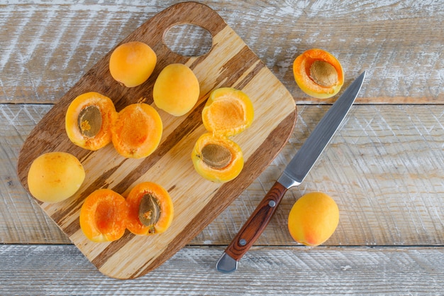 Apricots with knife on wooden and cutting board, flat lay.