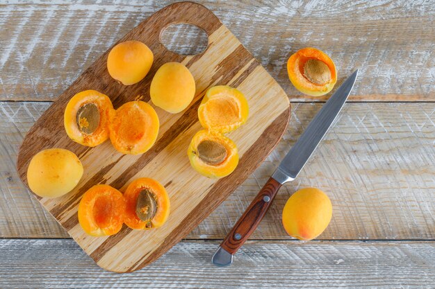 Apricots with knife on wooden and cutting board, flat lay.