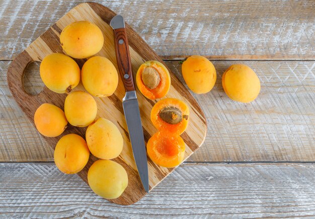 Apricots with knife on wooden and cutting board, flat lay.