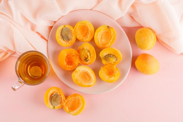 Apricots with tea in a plate, flat lay.