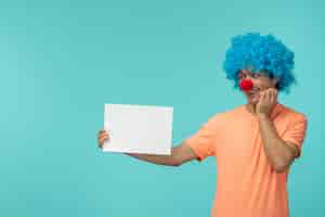 Free photo april fools day guy clown happy hand on chin holding paper blue hair excited funny red nose