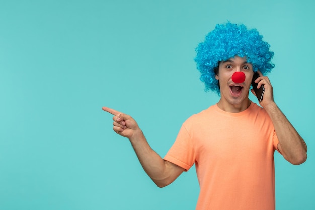 April fools day guy clown talking on the phone blue hair pointing finger to left funny red nose
