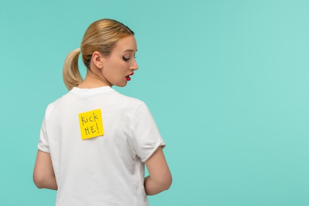 April fools day surprised blonde girl looking back on yellow post it sticker note kick me funny