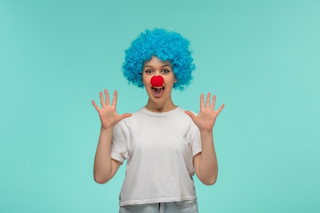 День дурака удивил девушку ладонями вверх открытым ртом с красным носом в костюме клоуна с синими волосами