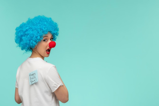 Free photo april fools day surprised girl with red nose blue post it on white tshirt clown costume blue hair