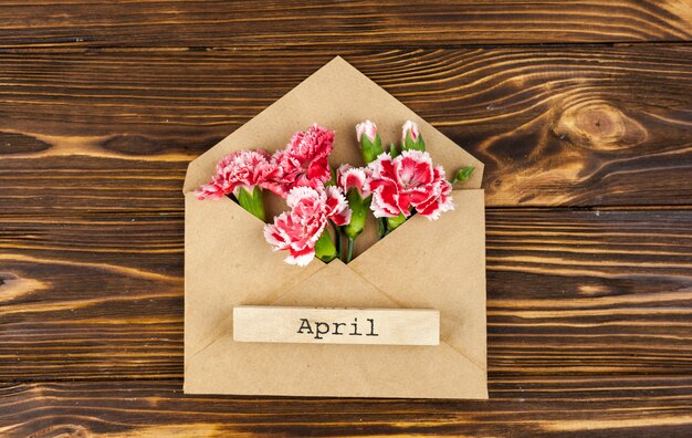테이블에 붉은 꽃 봉투에 4 월 텍스트