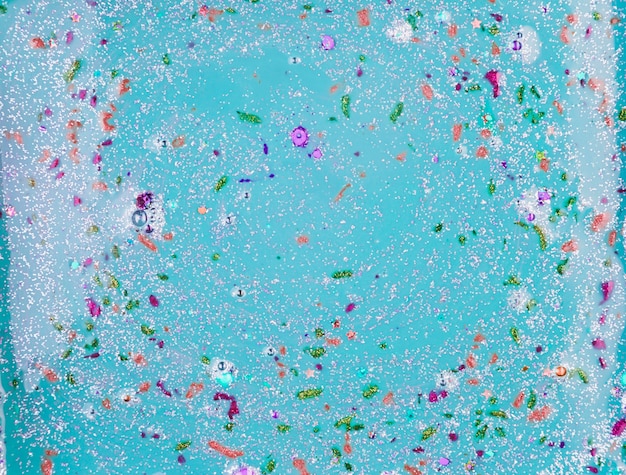 Aquamarine liquid with different colourful crumbs