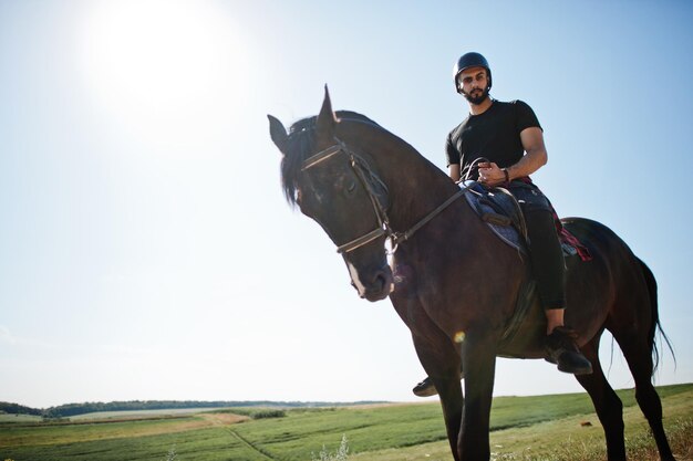 Arab tall beard man wear in black helmet ride arabian horse