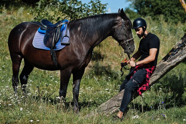 Arab tall beard man wear in black helmet with arabian horse