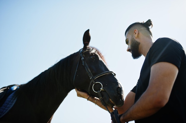 Арабский мужчина с высокой бородой в черном с арабской лошадью