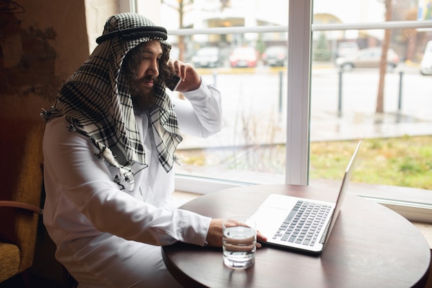 Foto gratuita uomo d'affari arabo che lavora in ufficio, business center utilizzando gadget devicesm. stile di vita