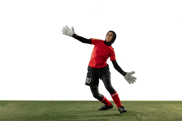 Arabian female soccer or football player, goalkeeper on white studio background.